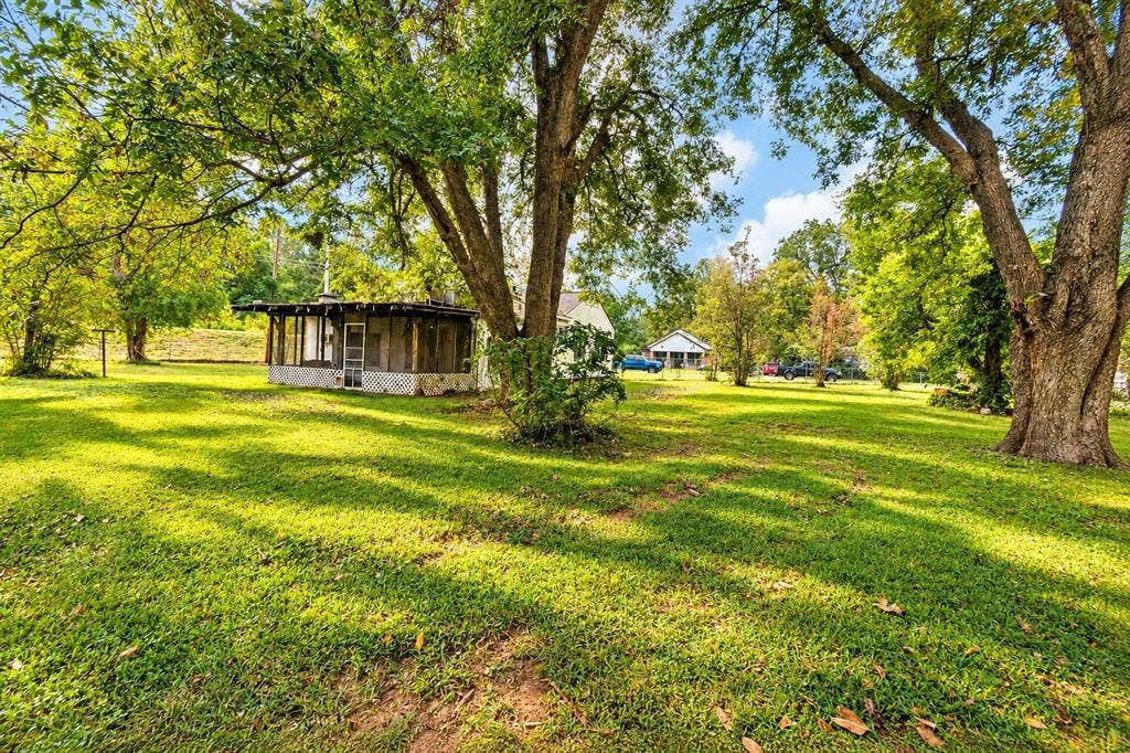 Expansive grounds featuring mature shade trees and a structure with a screened-in porch