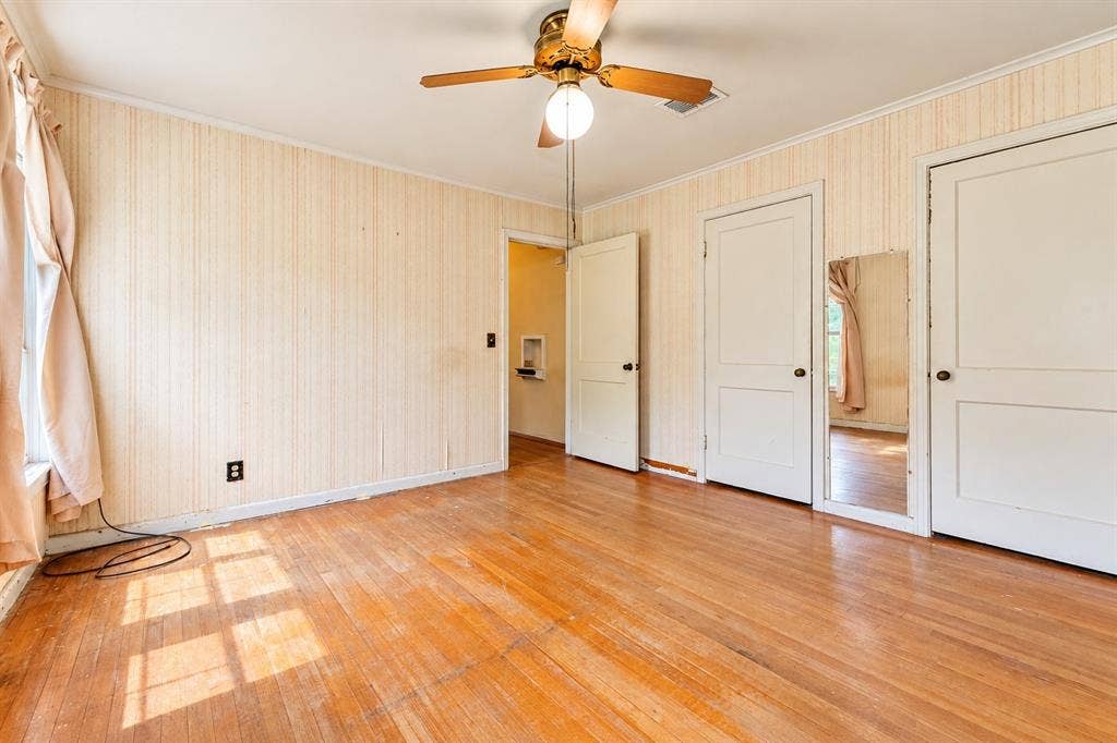 Hardwood flooring, ceiling-mounted paddle fan with light fixture, and multiple two-panel interior doors
