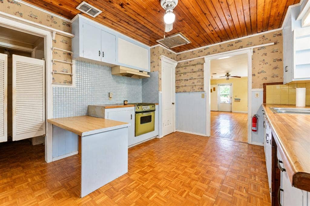 Kitchen featuring wood-plank ceiling, parquet wood-finish flooring, tiled backsplash, built-in cabinetry, and integrated oven