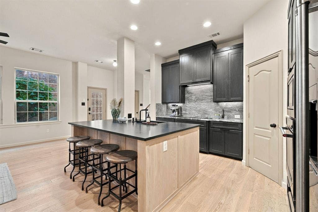 Kitchen featuring a center island with a stone countertop, dark cabinetry, recessed lighting, and wood-finish flooring