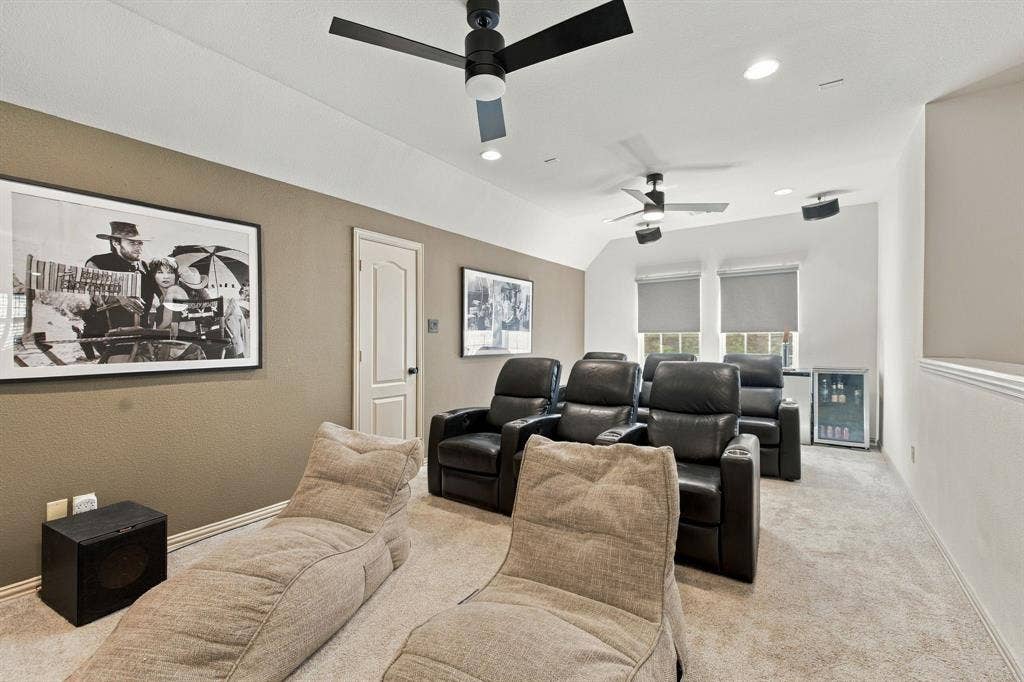 Multi-purpose room featuring dual ceiling fans, recessed lighting, integrated wall-mounted speakers, and a built-in beverage refrigerator