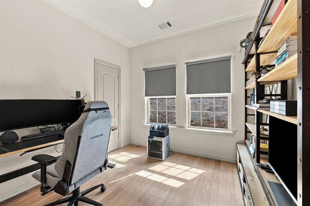 Room featuring wood-finish flooring, two multi-pane windows with integrated shades, and a solid-core interior door