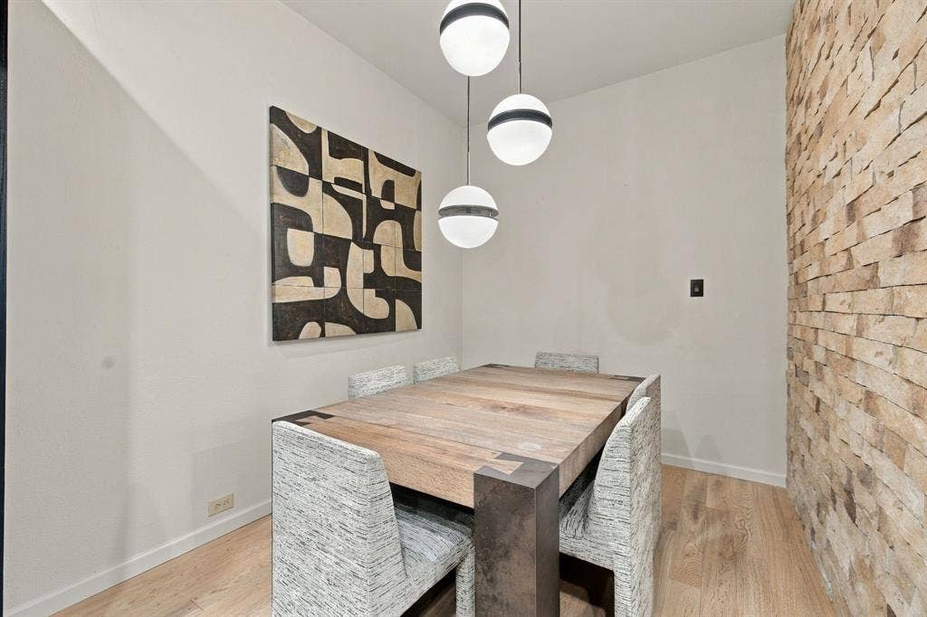 Textured stone accent wall paired with wood-finish flooring and three-tiered spherical pendant lighting