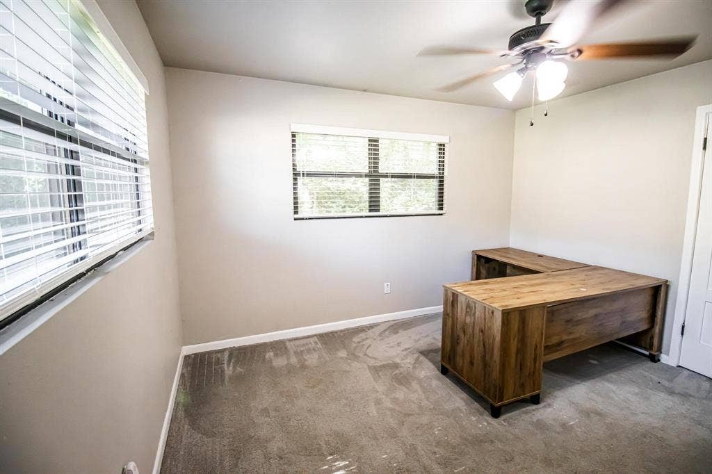 1040 Wedgewood Drive, Woodway, TX 76712 Neutral-toned room featuring neutral wall-to-wall carpeting, dual windows with horizontal blinds, and a ceiling-mounted light fixture with fan