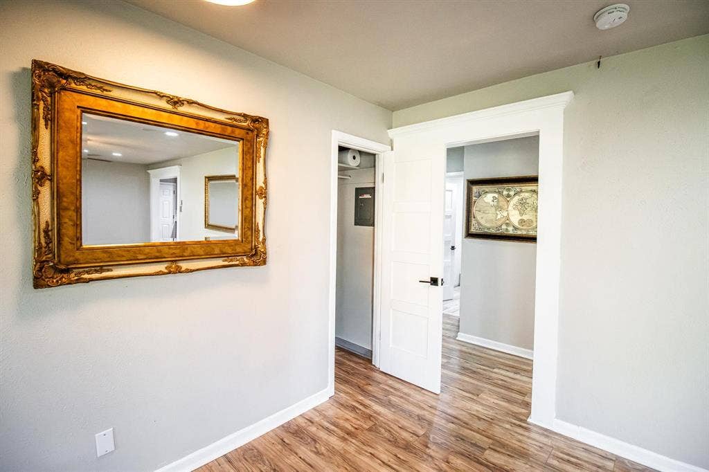 1040 Wedgewood Drive, Woodway, TX 76712 Four-panel interior door with matte black hardware, crisp white door casing, and wood-finish flooring