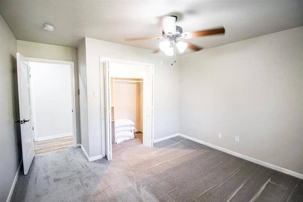 1040 Wedgewood Drive, Woodway, TX 76712 Neutral-toned interior featuring wall-to-wall carpeting, bi-fold closet doors, a multi-blade ceiling fan with integrated lighting, and white interior doors with matte black hardware
