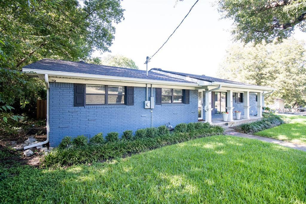 1040 Wedgewood Drive, Woodway, TX 76712 Single-story residence featuring blue painted brick exterior, covered front porch with square columns, and mature landscaping