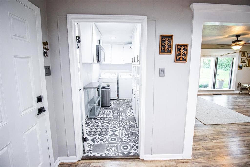 1040 Wedgewood Drive, Woodway, TX 76712 Utility room featuring geometric patterned floor tile, white built-in cabinetry, and wood-finish flooring