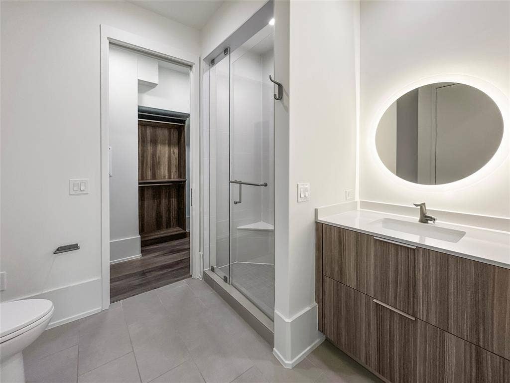 Bathroom featuring walk in shower, tile patterned floors, toilet, and vanity