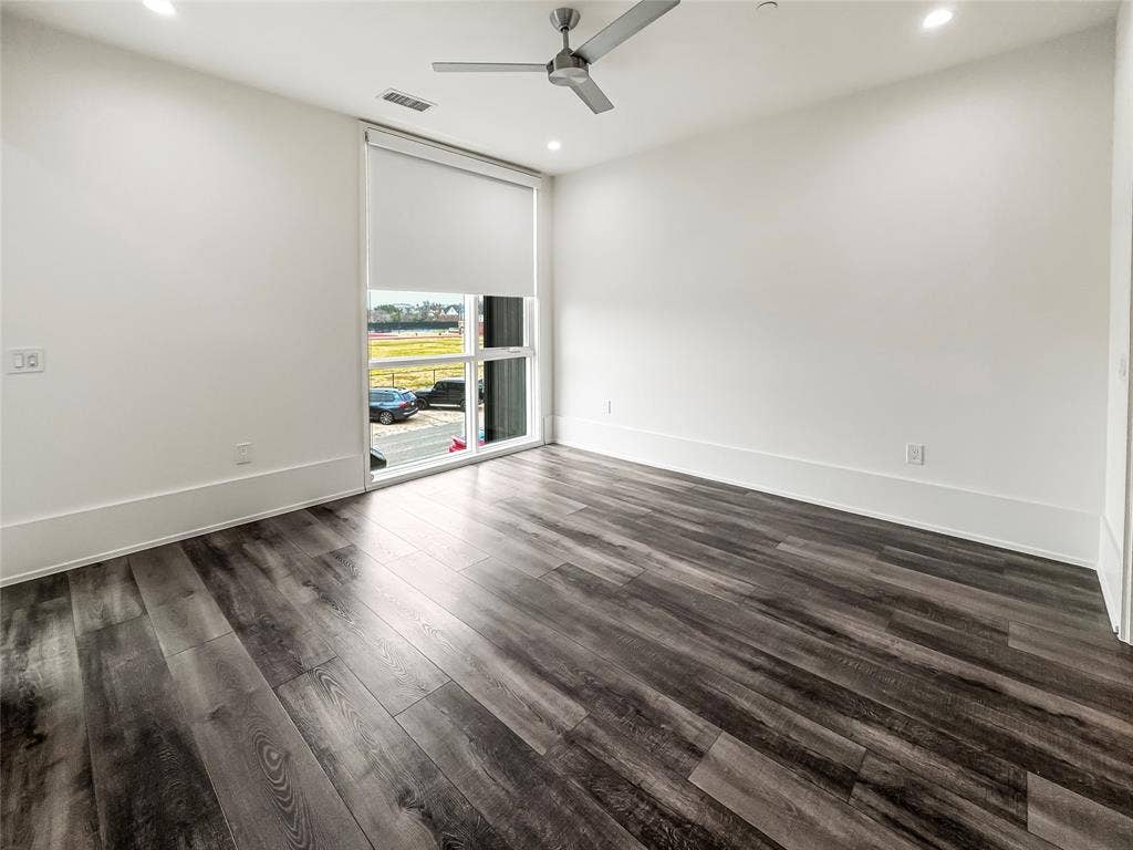 Spare room with dark wood-type flooring, ceiling fan, and a wall of windows