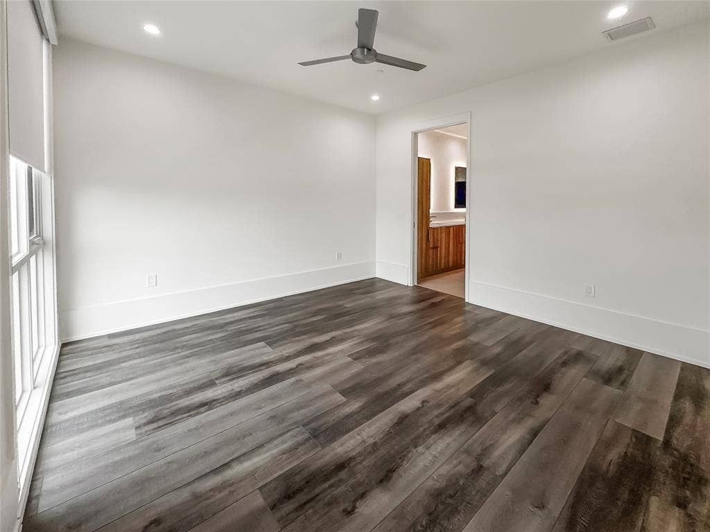 Unfurnished room featuring dark wood-type flooring and ceiling fan