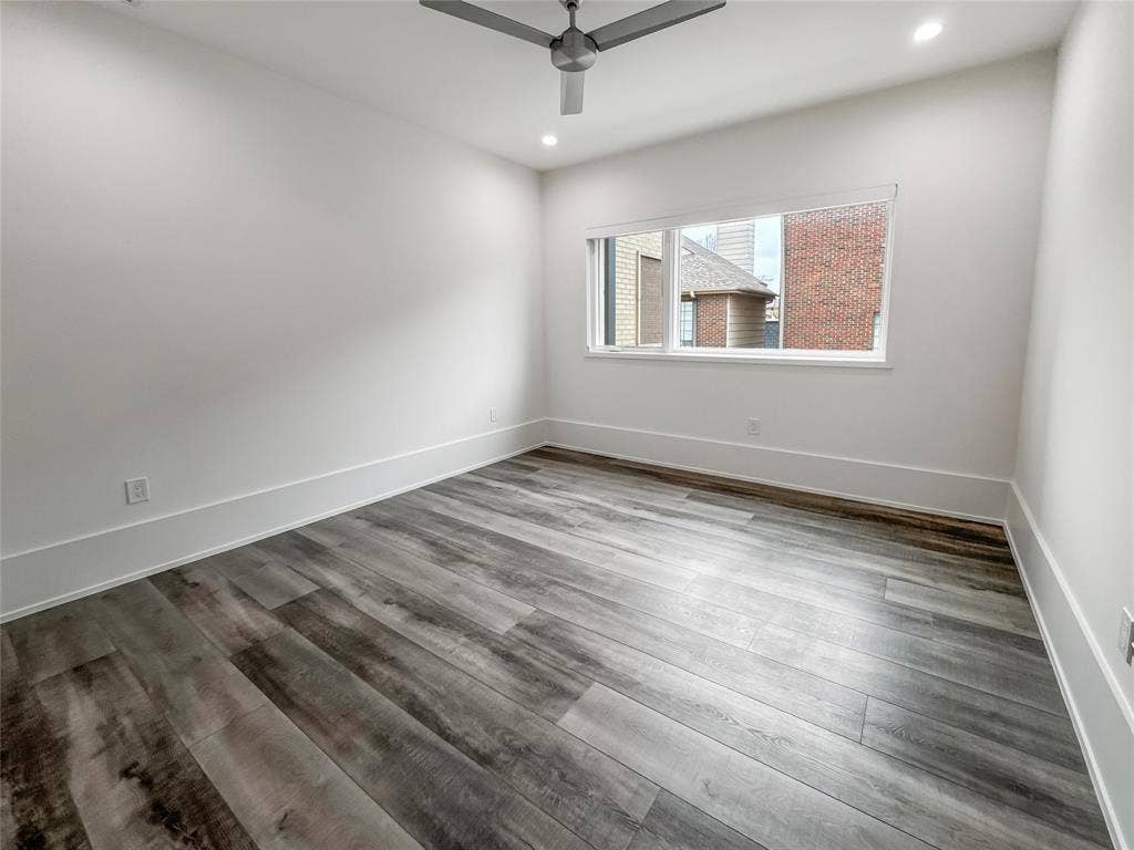 Empty room with ceiling fan and dark hardwood / wood-style flooring