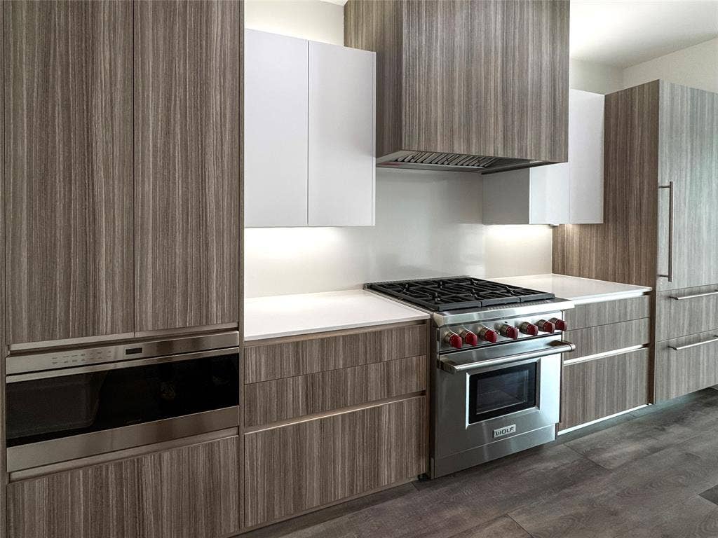 Kitchen with stainless steel appliances, white cabinetry, dark hardwood / wood-style floors, and ventilation hood