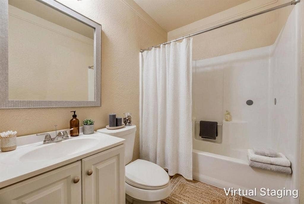 Bathroom featuring a white vanity cabinet with an integrated sink, polished chrome faucet, framed mirror, and a white tub and shower combination
