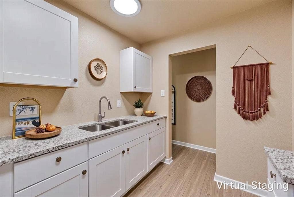 White cabinetry featuring brushed hardware, speckled stone-finish countertops, stainless steel dual-basin undermount sink, gooseneck faucet, and wood-finish flooring