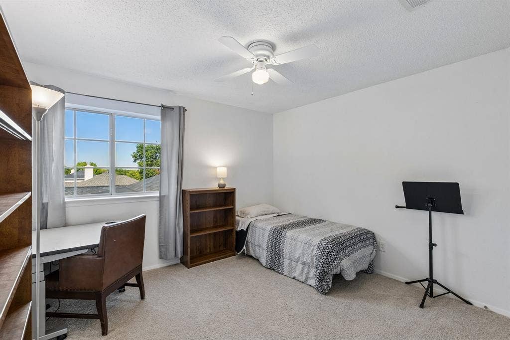 Neutral-toned carpeting, white walls, and a ceiling-mounted light fixture with a fan
