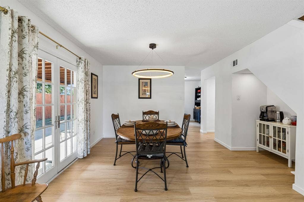 Dining area featuring wood-finish flooring, a modern circular LED pendant light, and double glass-paned doors