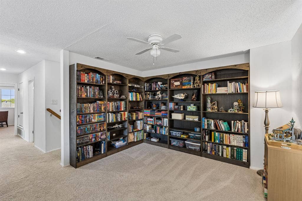 Custom-built floor-to-ceiling wooden shelving units with arched detailing and a ceiling fan with integrated lighting
