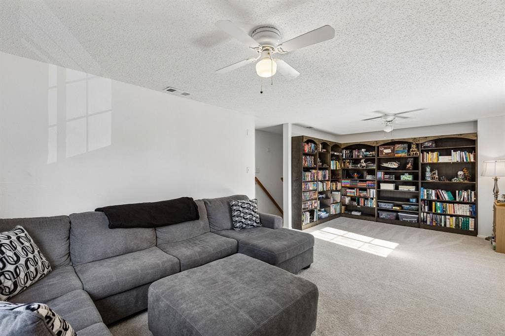 Built-in full-wall shelving, dual ceiling fans, and neutral wall-to-wall carpeting