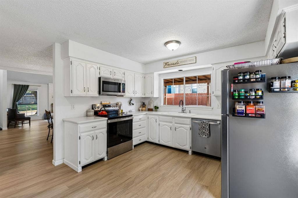 Kitchen featuring white cabinetry, stainless steel appliances, wood-finish flooring, a double-basin sink, and recessed lighting