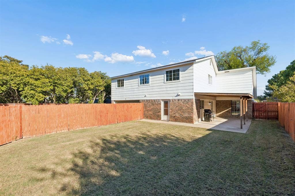 Backyard featuring a privacy fence, covered concrete patio, and brick and siding exterior
