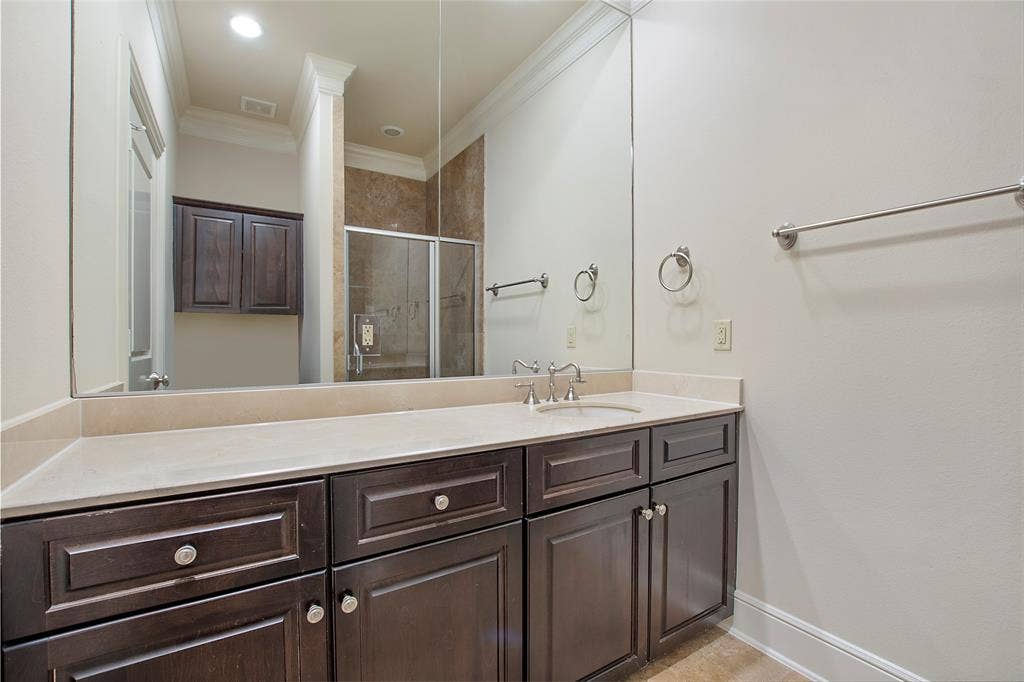 Bathroom featuring a shower with door, ornamental molding, and vanity