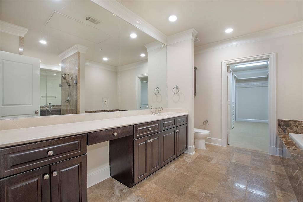 Full bathroom featuring vanity, toilet, crown molding, and plus walk in shower