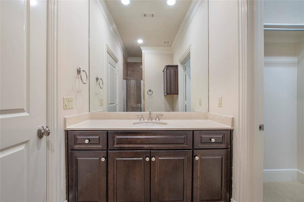 Bathroom featuring vanity, crown molding, and a shower with shower door