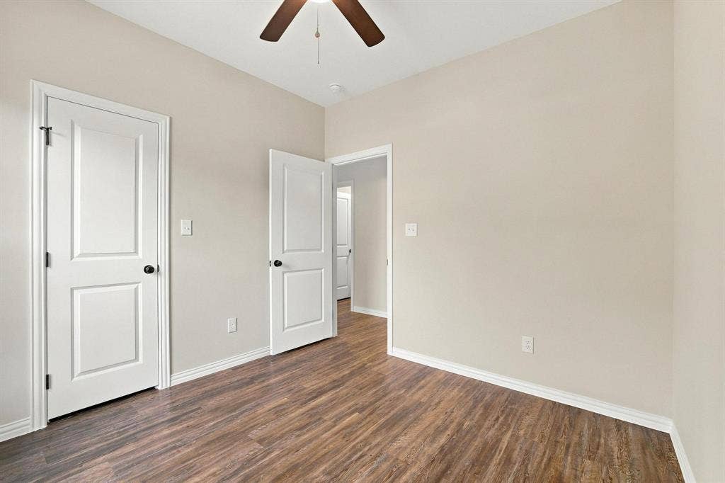 1116 S 6th Avenue, Denison, TX 75021 Room featuring wood-finish flooring, two-panel interior doors, and a ceiling-mounted paddle fan