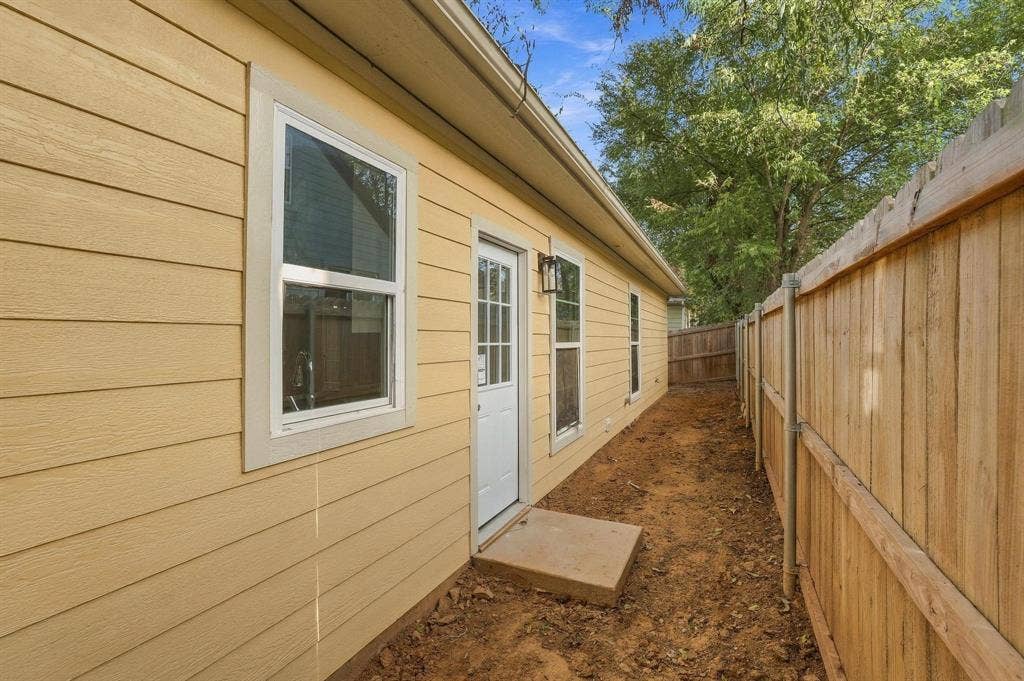 1116 S 6th Avenue, Denison, TX 75021 Horizontal lap siding exterior with a white-framed single entry door, concrete threshold, and wood privacy fencing