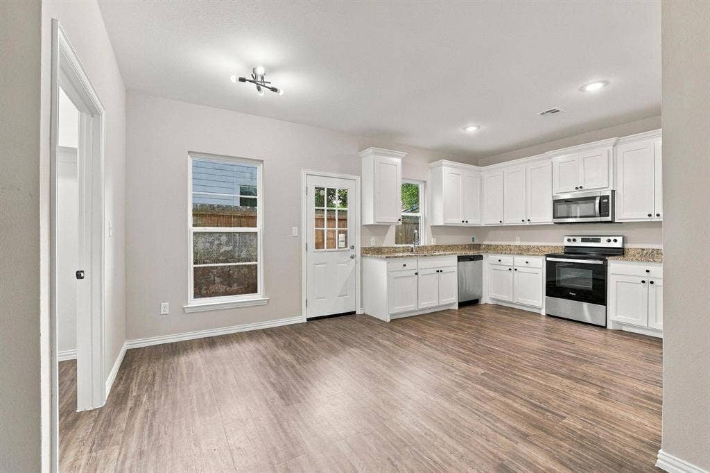 1116 S 6th Avenue, Denison, TX 75021 Kitchen featuring white shaker-style cabinetry, stone-finish countertops, stainless steel appliances, and wood-finish flooring
