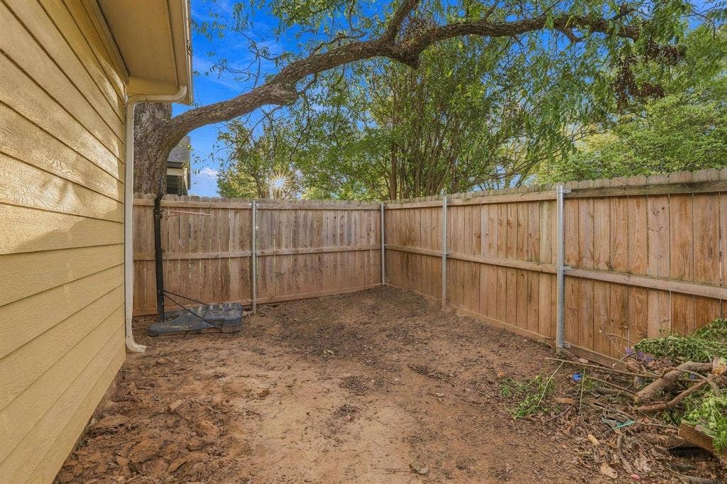 1116 S 6th Avenue, Denison, TX 75021 Exterior side yard featuring horizontal lap siding, a wood-panel privacy fence, and mature trees