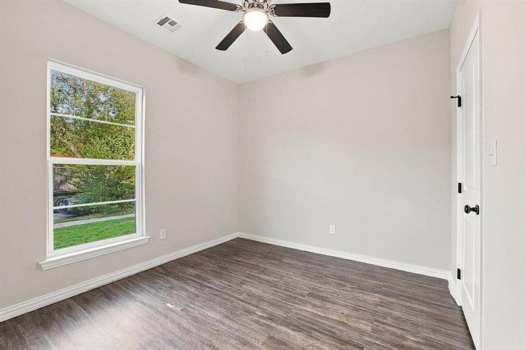 1116 S 6th Avenue, Denison, TX 75021 Interior space featuring wood-finish flooring, a single-hung window with muntins, a ceiling fan with integrated lighting, and a solid-core door with matte black hardware
