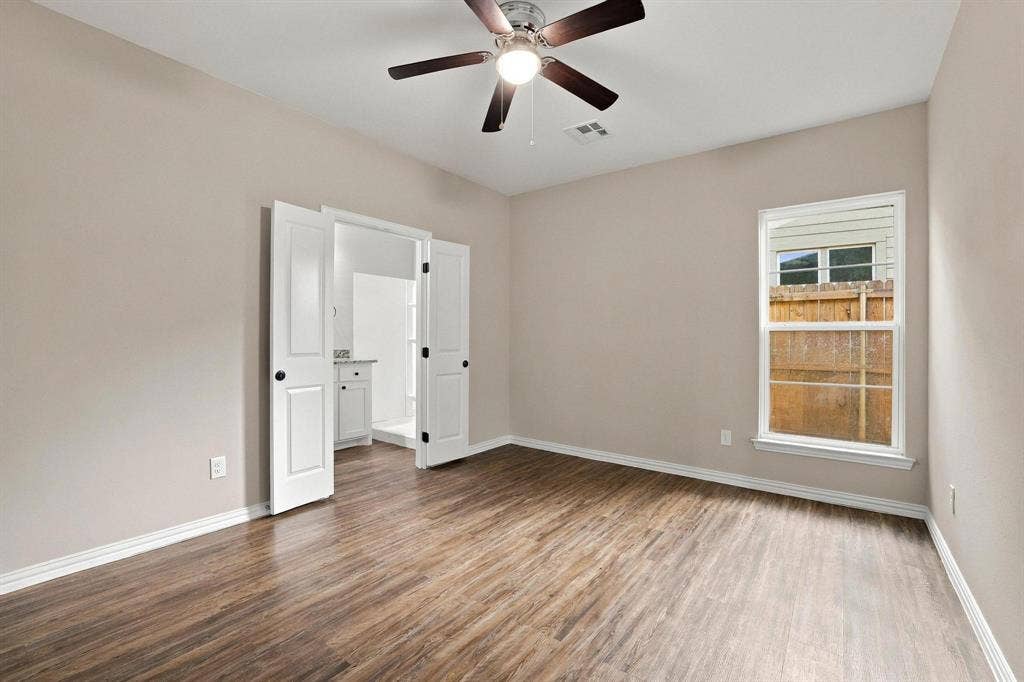 1116 S 6th Avenue, Denison, TX 75021 Neutral-toned room featuring wood-finish flooring, a multi-blade ceiling fan with integrated lighting, and dual hinged doors