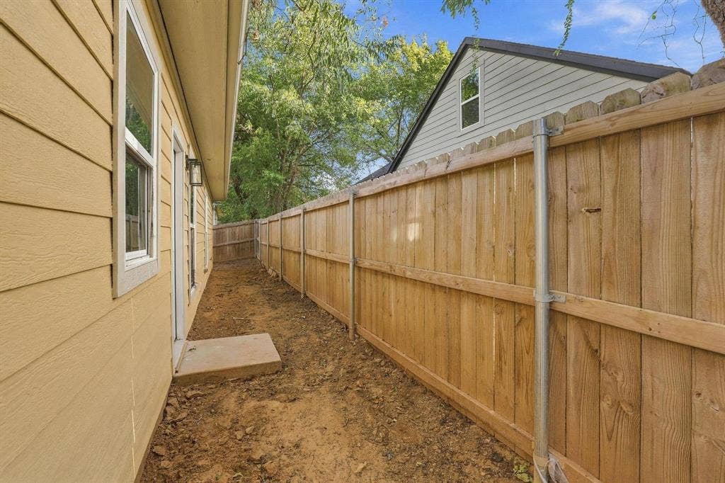1116 S 6th Avenue, Denison, TX 75021 Side yard featuring horizontal lap siding, a concrete landing, and a wood privacy fence with metal support posts