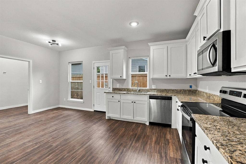 1116 S 6th Avenue, Denison, TX 75021 Kitchen featuring white cabinetry, stone-finish countertops, stainless steel appliances, and wood-finish flooring