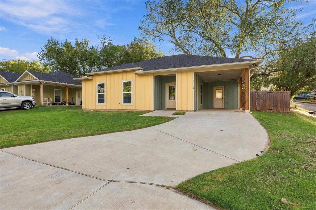 1116 S 6th Avenue, Denison, TX 75021 Single-story exterior featuring vertical board-and-batten siding, a covered entryway, a concrete driveway, an attached carport, and a wood privacy fence