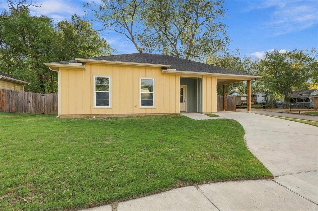 1116 S 6th Avenue, Denison, TX 75021 Single-story exterior featuring vertical board-and-batten siding, a covered carport, a concrete driveway, and a fenced yard