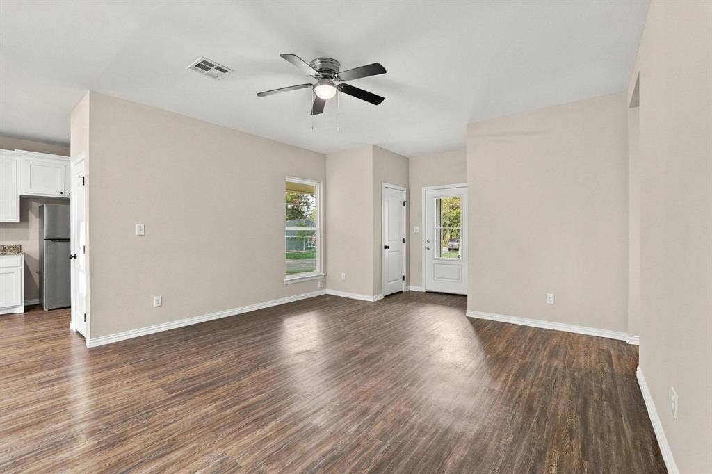 1116 S 6th Avenue, Denison, TX 75021 Open interior space featuring wood-finish flooring, neutral wall paint, a central ceiling fan with integrated lighting, and a glass-paneled exterior door