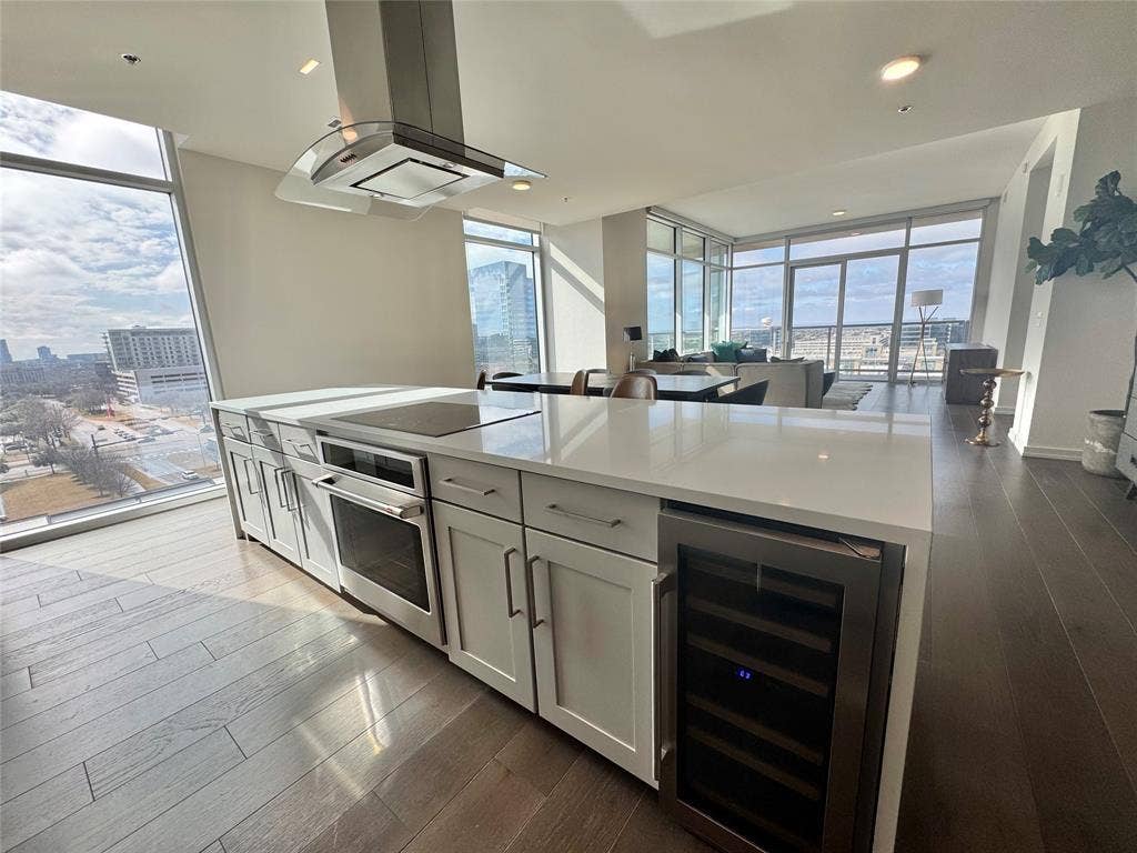 6911 Cowboys Way, #913, Frisco, TX 75034 Kitchen with a wall of windows, beverage cooler, stainless steel oven, and island exhaust hood