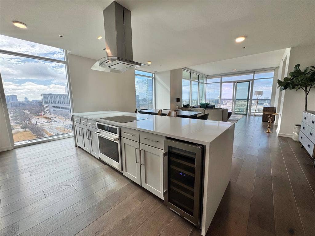 6911 Cowboys Way, #913, Frisco, TX 75034 Kitchen with island range hood, white cabinetry, oven, beverage cooler, and a wall of windows