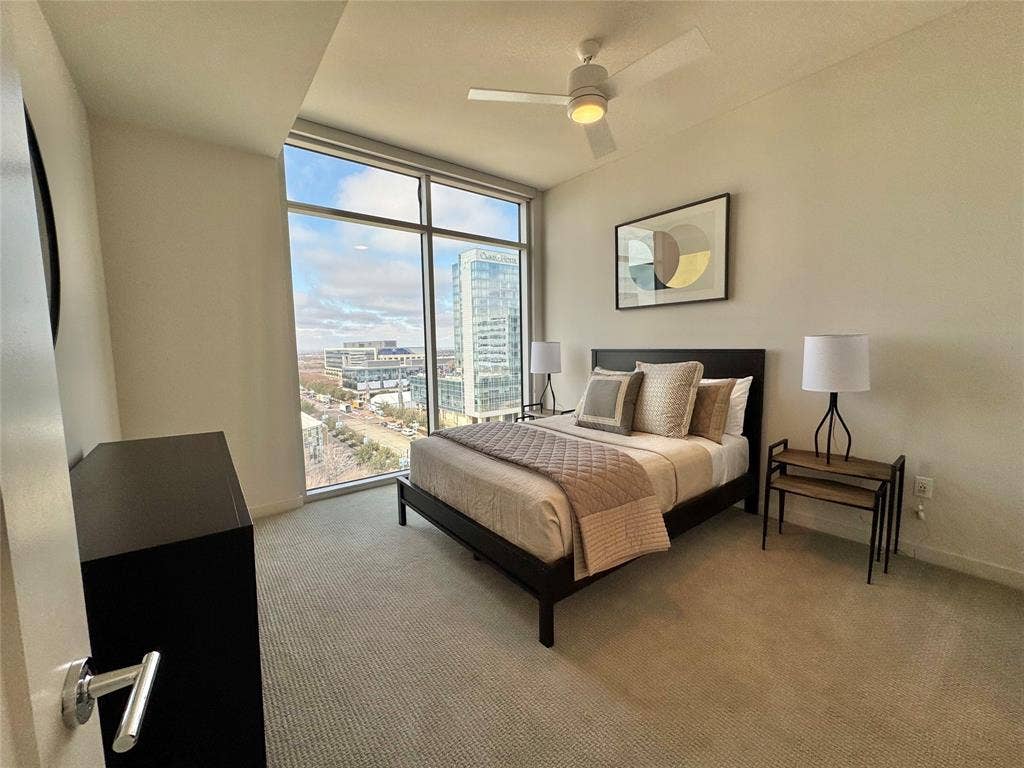 6911 Cowboys Way, #913, Frisco, TX 75034 Bedroom with expansive windows, light colored carpet, and ceiling fan