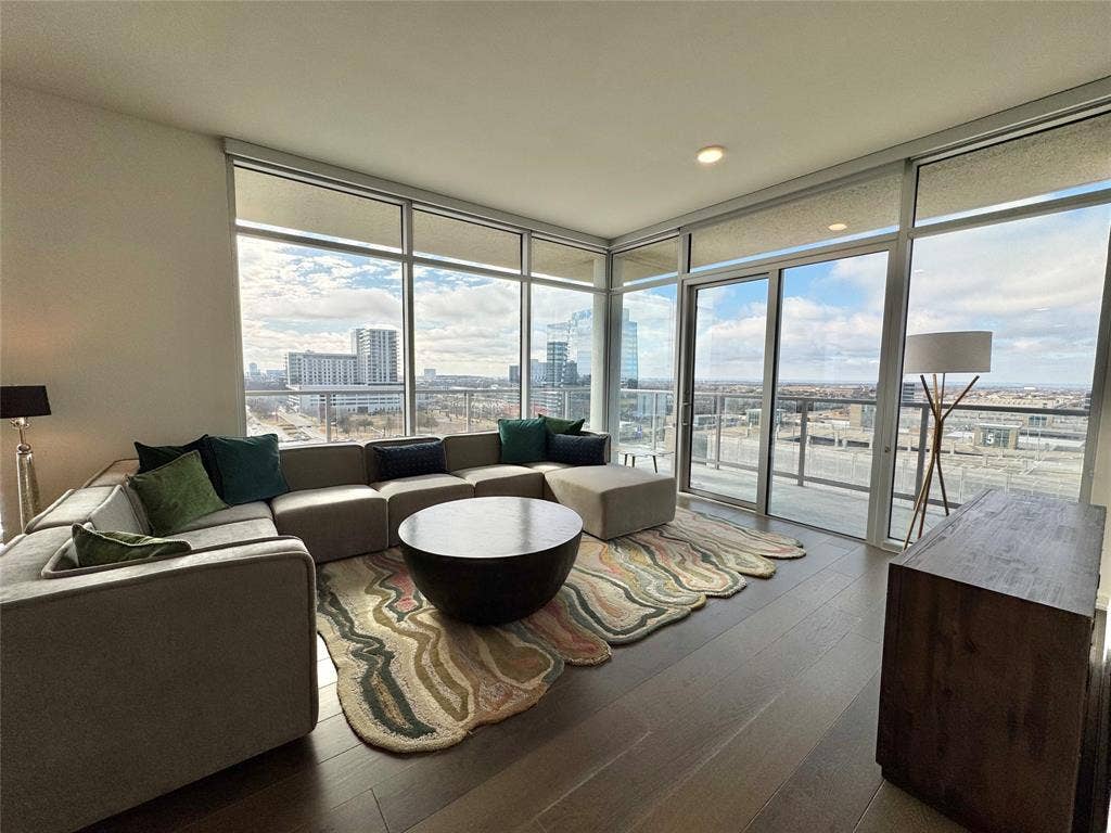 6911 Cowboys Way, #913, Frisco, TX 75034 Living room featuring expansive windows, a healthy amount of sunlight, and hardwood / wood-style floors
