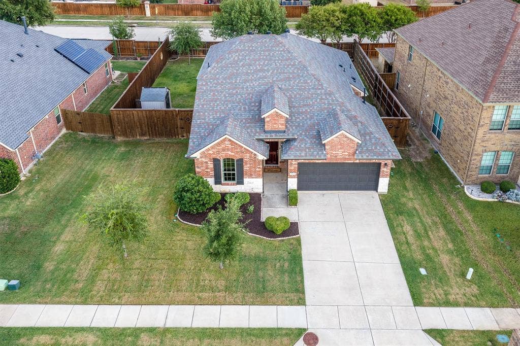 3014 Aurora Mist Drive, Little Elm, TX 75068 Brick exterior featuring a multi-gabled roofline, front-facing two-car garage, concrete driveway, and landscaped front yard