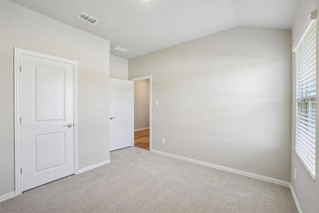 6110 CHICKNEY Drive, Princeton, TX 75071 Room featuring a vaulted ceiling, neutral wall tones, carpeted flooring, and a window with horizontal blinds