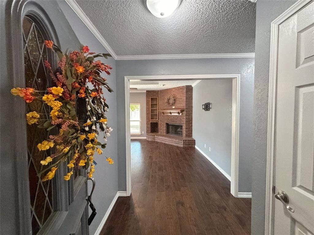 Entryway featuring an arched door with decorative glass inlay, wood-finish flooring, and a brick corner fireplace with integrated shelving