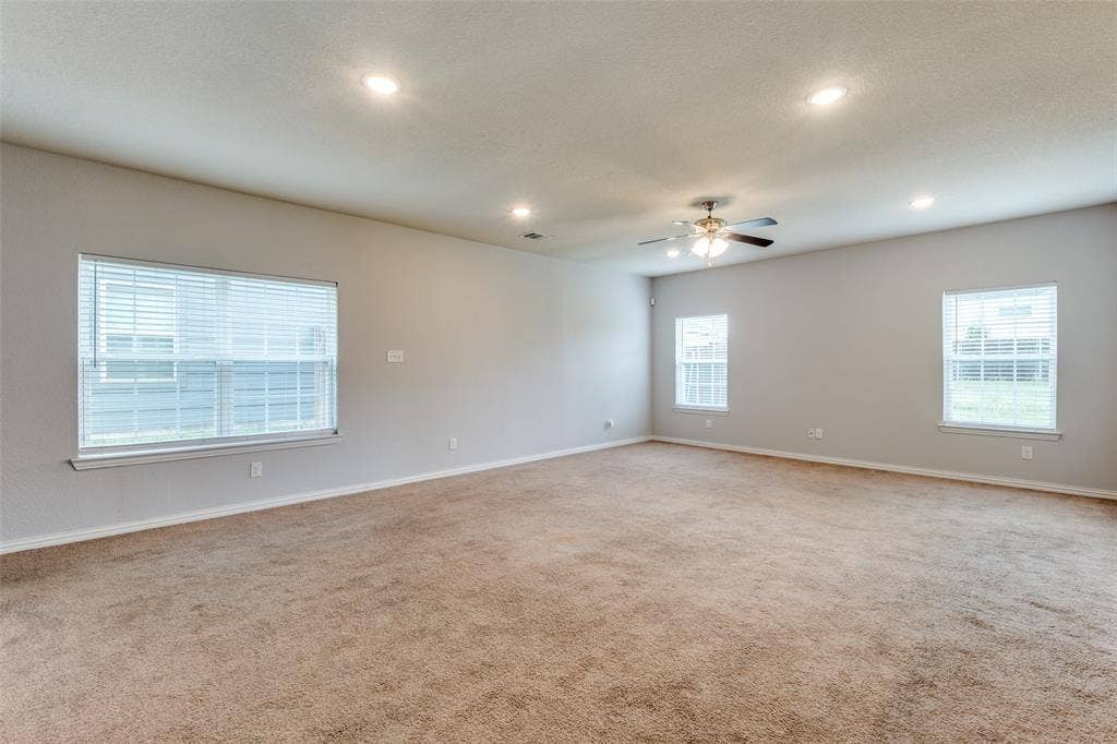 4662 Ralph Lane, Dallas, TX 75227 Spacious room featuring neutral carpeting, recessed lighting, a ceiling fan with integrated light fixture, and multiple windows with horizontal blinds
