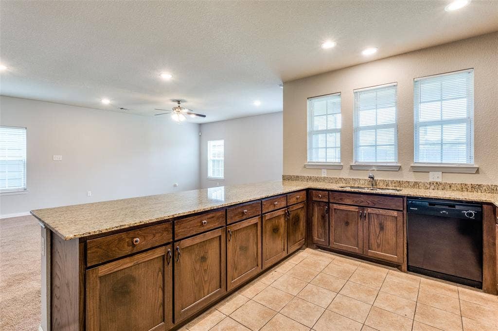 4662 Ralph Lane, Dallas, TX 75227 Kitchen featuring wood cabinetry, stone-finish countertops, tile flooring, recessed lighting, and a built-in dishwasher