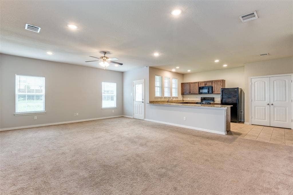4662 Ralph Lane, Dallas, TX 75227 Open-concept interior featuring recessed lighting, a ceiling fan, stone-surfaced breakfast bar, wood-finish cabinetry, and neutral carpeting
