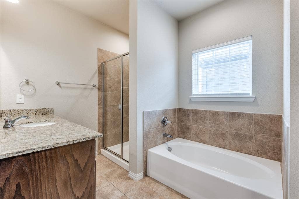 4662 Ralph Lane, Dallas, TX 75227 Bathroom featuring a granite countertop vanity, a tiled walk-in shower with a glass enclosure, a deep soaking tub with a tiled surround, and a window with blinds